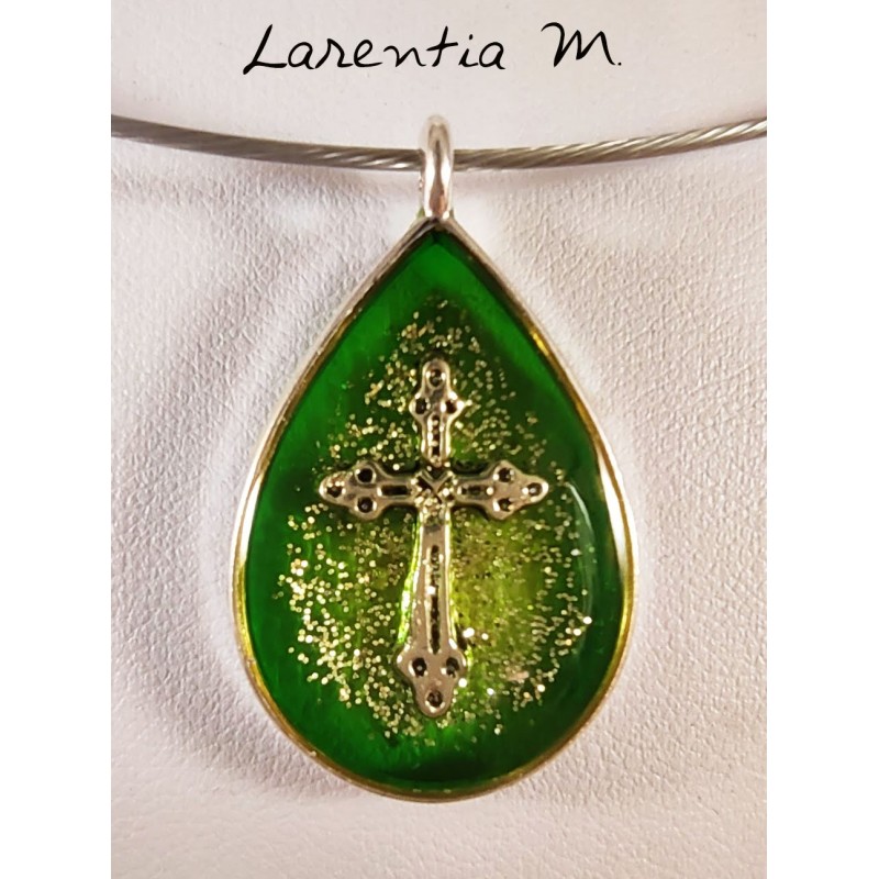 Collier pendentif argenté, inclusion résine avec croix argentée, fond vert et paillettes argent. Ras de cou fil métal argenté. Collier pendentif argenté, inclusion résine avec croix argentée, fond vert et paillettes argent. Ras de cou fil métal argenté.