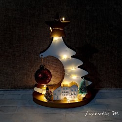Large ceramic Christmas tree on a stand, with a Christmas bauble, a small village, a snowman, and string lights